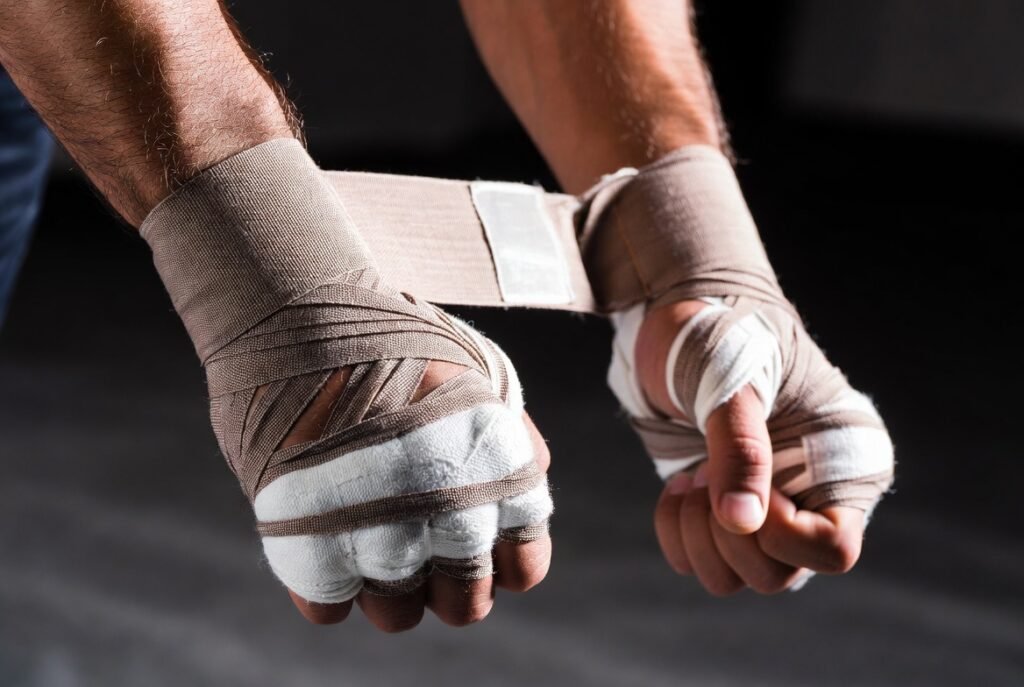 Inner Glove Wraps vs. Traditional Hand Wraps:Which is Better 1 1 **Alt text:**Ultra-realistic cinematic close-up of a modern athlete’s hands professionally wrapped in beige gel inner boxing glove wraps. Thick knuckle padding and long semi-elastic wrist straps are tightly secured. Dramatic studio lighting highlights the fabric texture and stitching details, with a clean dark athletic background and shallow depth of field. Professional sports photography style.